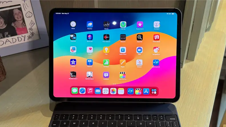 A photo of the 2024 iPad Pro attached to a Magic Keyboard. The tablet is sitting on a desk.