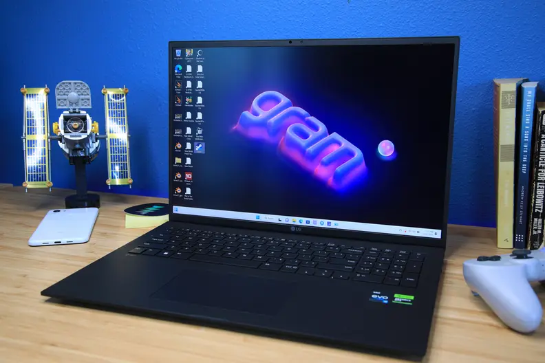 A black laptop open and powered on sitting on top of a light brown wood desk
