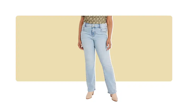 A model seen from the waist down, wearing light wash boot-cut jeans with a printed green top.