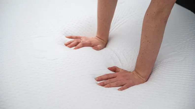 a person's hands press into the surface of the Puffy Lux Hybrid