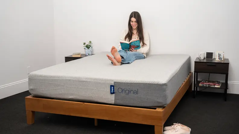 a person sits and reads on the casper original mattress