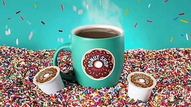 A coffee mug with Keurig's Donut Shop logo on it, with a K-cup on each side.