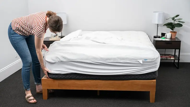 a person puts on a mattress protector