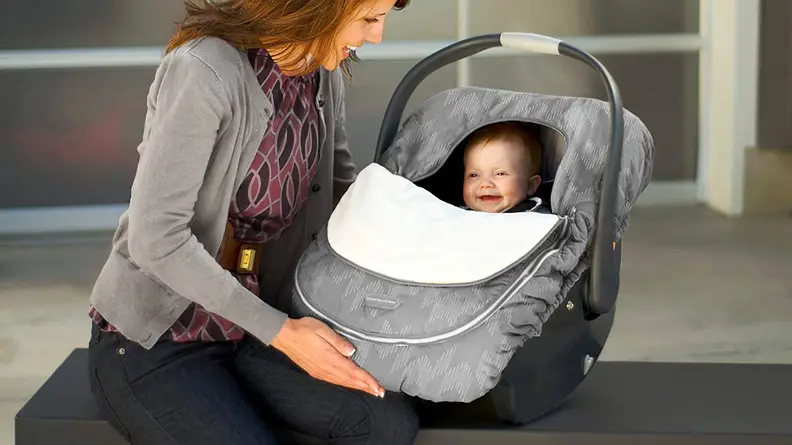 A baby in a car seat that has a cover on it.