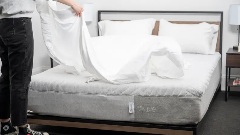 A person spreading sheets on top of a mattress
