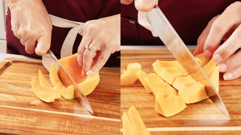 Person using knife to cut butternut squash into spears and cubes on top of wooden cutting board.