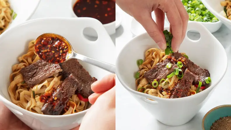 Cooked ramen noodles inside of porcelain bowl with garnishes on top.