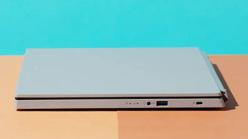 The Acer Aspire Vero, closed, sitting on an orange table with a baby blue background.