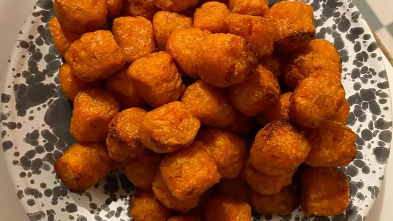 A bowl of crispy sweet potato tater tots.
