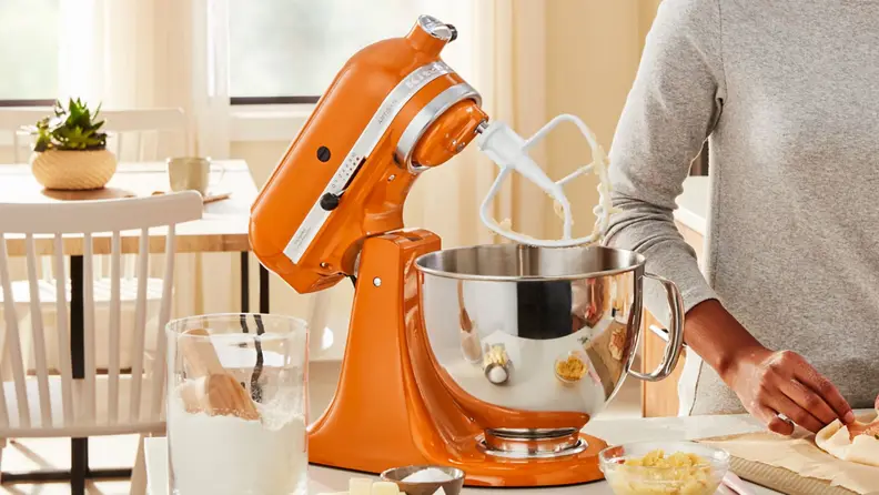 An orange stand mixer with its head tilted