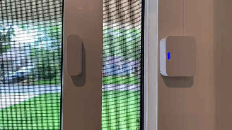 A SimpliSafe entry sensor installed on an open window.