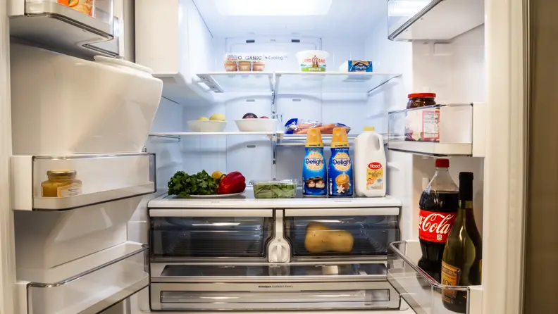 The Samsung RF28R6201SR is opened up, displaying shelves full of food. The left-hand door doesn't have nearly as much stored on it, however, as a large portion is taken up by the ice reservoir.