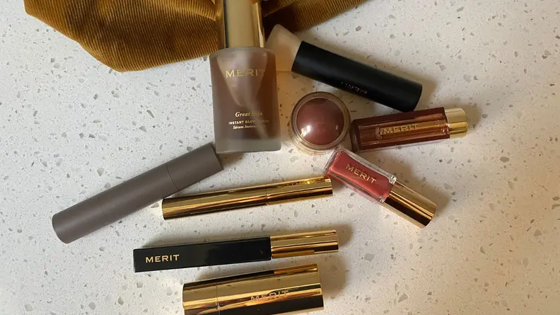 A smattering of makeup products laying on a speckled countertop.