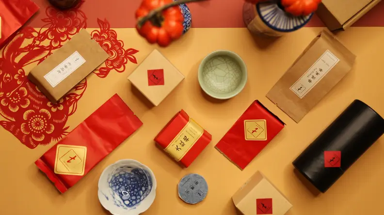 On a table, a few small bags of loose leaf tea are scattered around.
