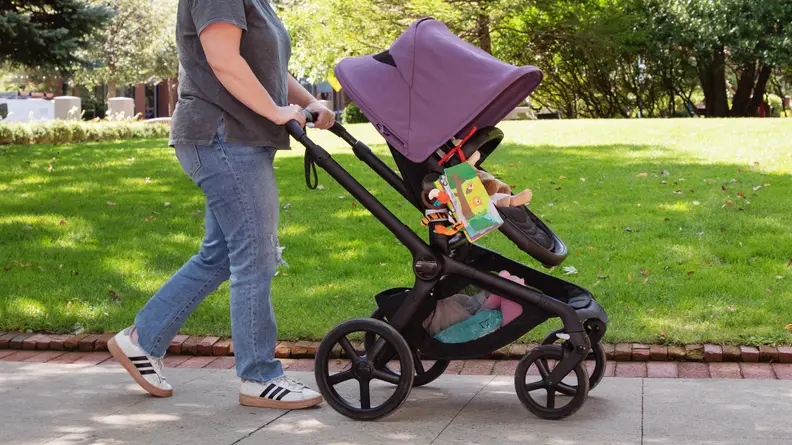 A woman walking in a park with the Bugaboo Fox 5 stroller in the color black.