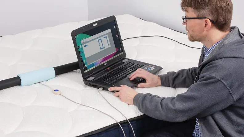 A person using a laptop and sensors to test the pressure point relief of the DreamCloud.
