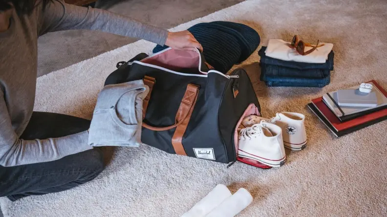 man packing up items in a black Herschel bag