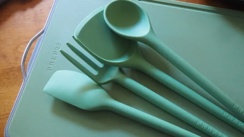 Green cooking utensils on green chopping board