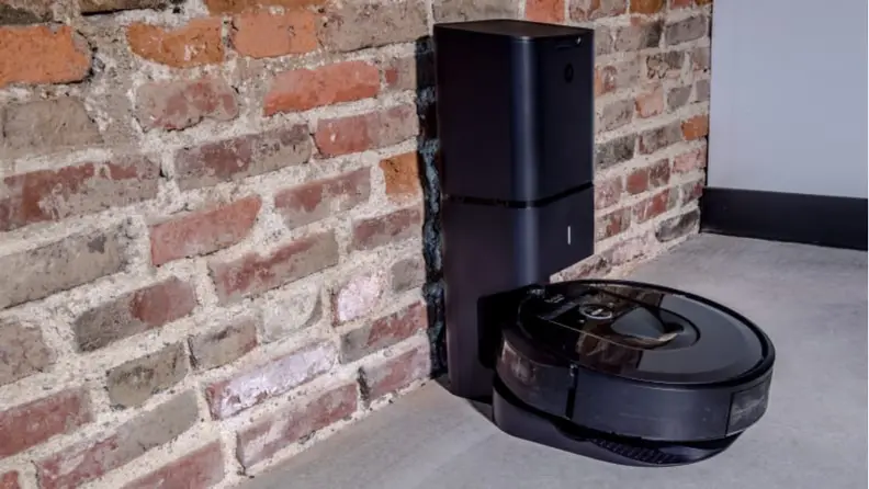 An iRobot i7+ against a brick wall.