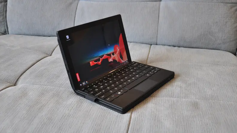 The X1 Fold sits atop a grey cushion, full assembled to its full stature, it's a tiny black bit of laptop with tiny peripherals to match.