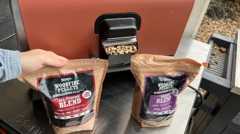 Two bags of Ninja Woodfire Pellets next to the "smoker box" on the Ninja Woodfire Outdoor Oven