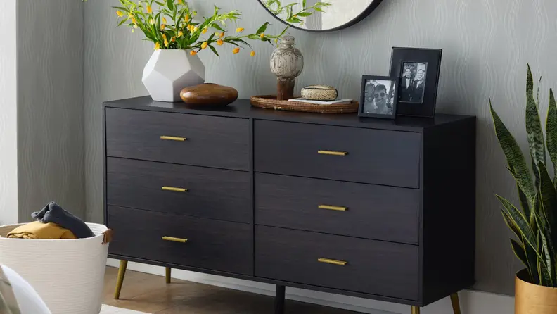 A brown cabinet set with some potted plants and framed photographs containing a gay couple.