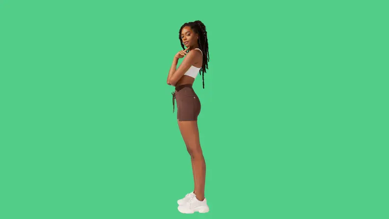 A model wearing brown athletic shorts and a white top.