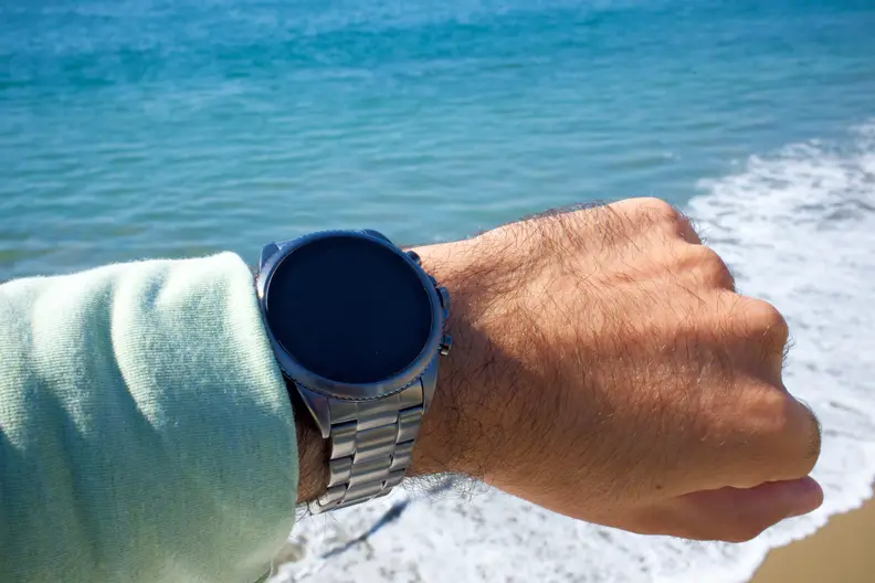 The Fossil Gen 6 being worn on a wrist, with the beach in the background.