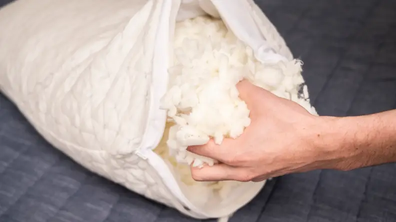 a hand pulling out filling from the Coop Home Goods Original Pillow