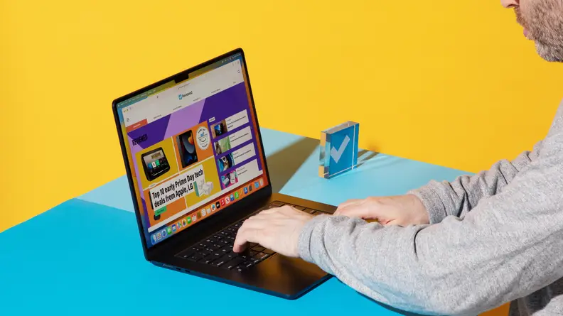 Person sitting at desk with blue surface while navigating the trackpad on the MacBook Air 15 M2 15-inch laptop.