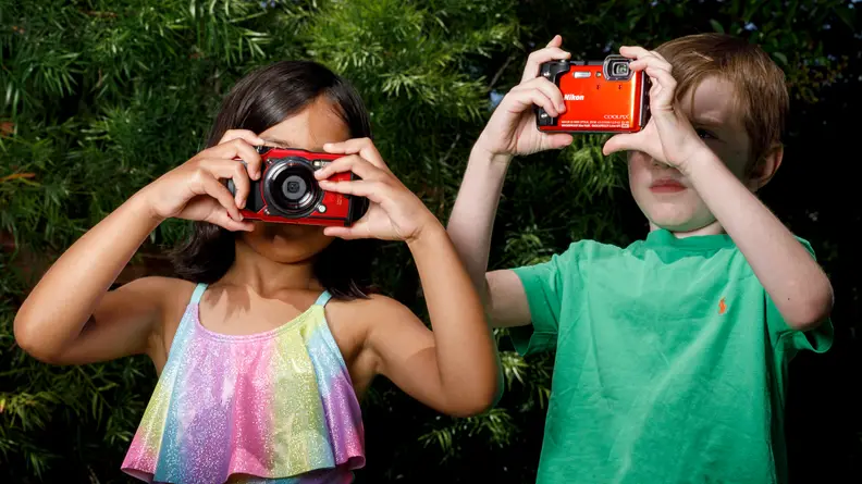 Two children look through camera viewfinders, including the Olympus Tough TG-6
