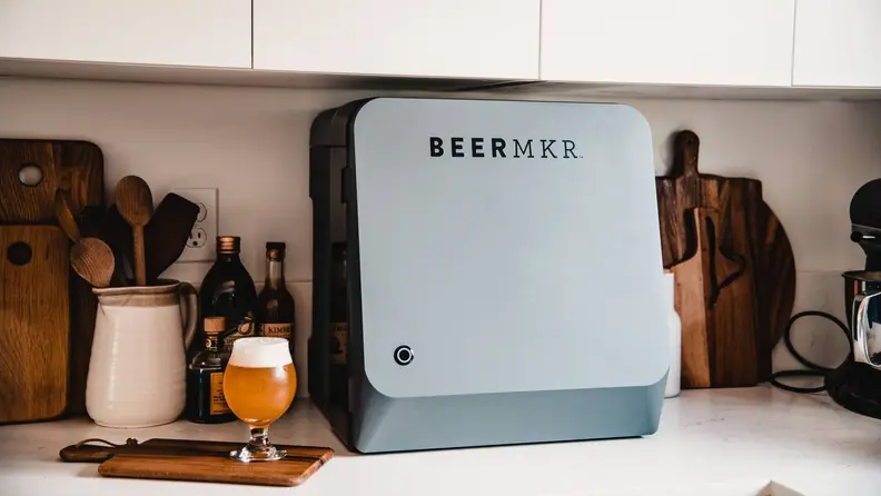 An automated beer brewing device sits on a kitchen counter.