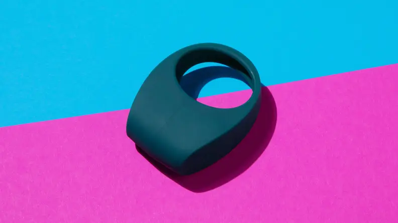 A blue Lelo Tor 2 vibrating cock ring on top of a two-tone pink and blue contrast surface.