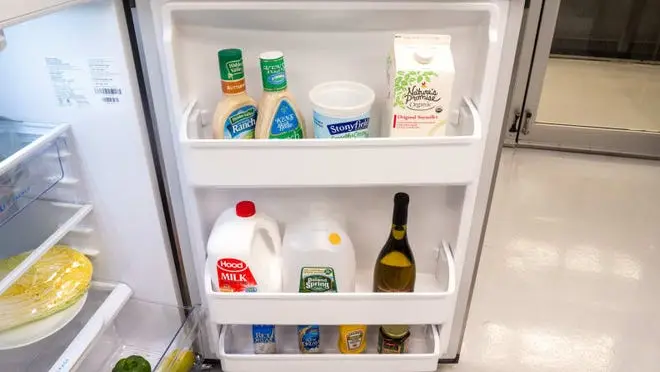 Silver refridgerator with door open showing food on shelves