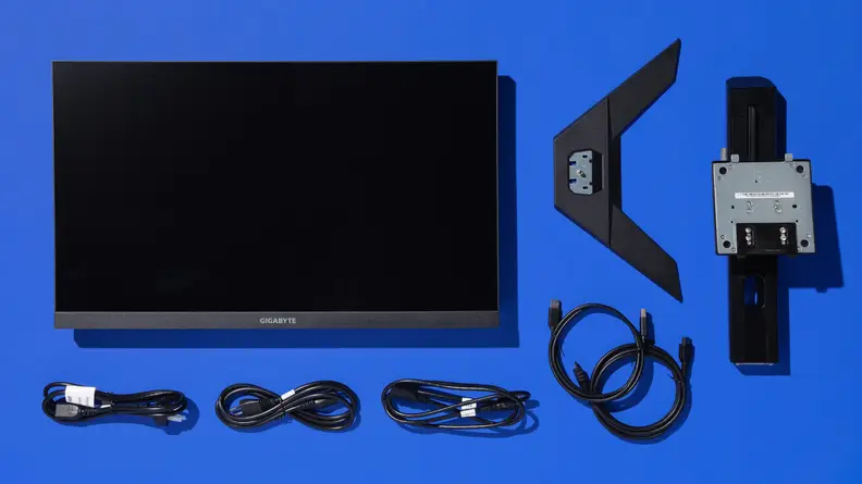 The Gigabyte M27U monitor laid out next to four cords, mount, and stand for the monitor.