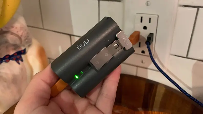 A hand holding a Ring doorbell battery.