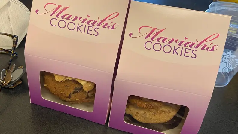 Two white and purple boxes of Mariah Carey's cookies sit on a kitchen counter.