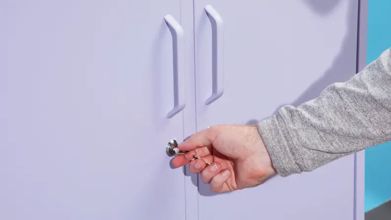 A person locking the doors of the Mustard Made locker with the key.