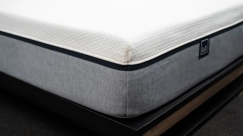 the corner of the lull mattress with a gray bottom fabric and white upper fabric