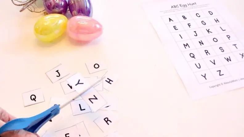 A printout of alphabet letters beside Easter eggs and scissors.