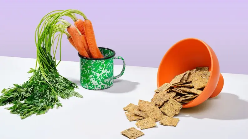 Bowls of carrots and chips sit on a surface.
