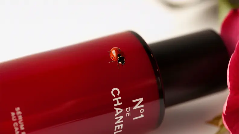 A red transparent cosmetic bottle tipped onto its side.
