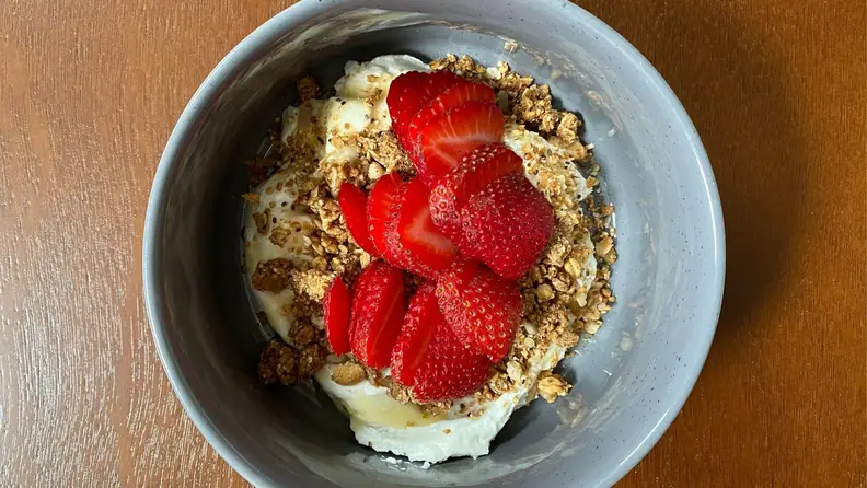 A bowl of granola, yogurt, and strawberries.