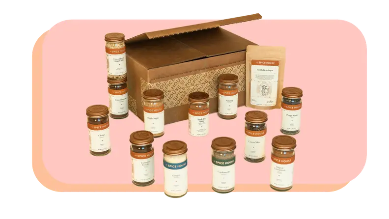 Twelve assorted spice jars next to cardboard box.