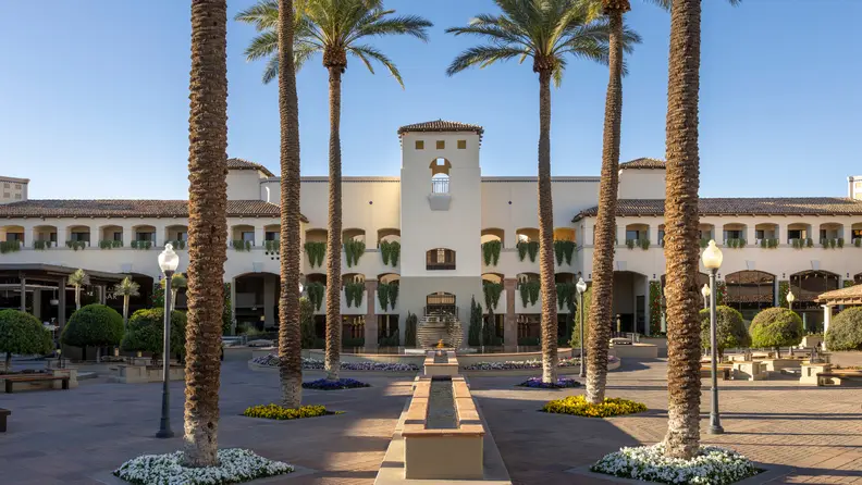 A hotel at the end of a long road surrounded by palm trees