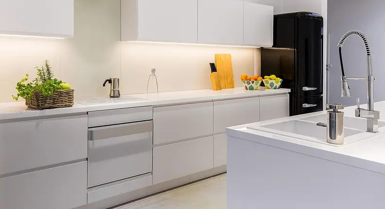The Eve Light Strip displayed in the color white and installed under kitchen cabinets