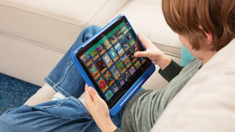 A kid on a couch looking at a selection of apps on the tablet.