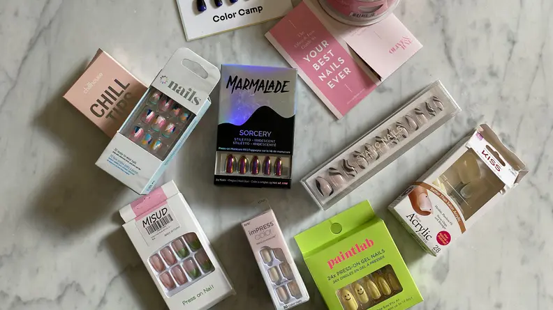 An array of press-on nail sets laid out on a marble tabletop.