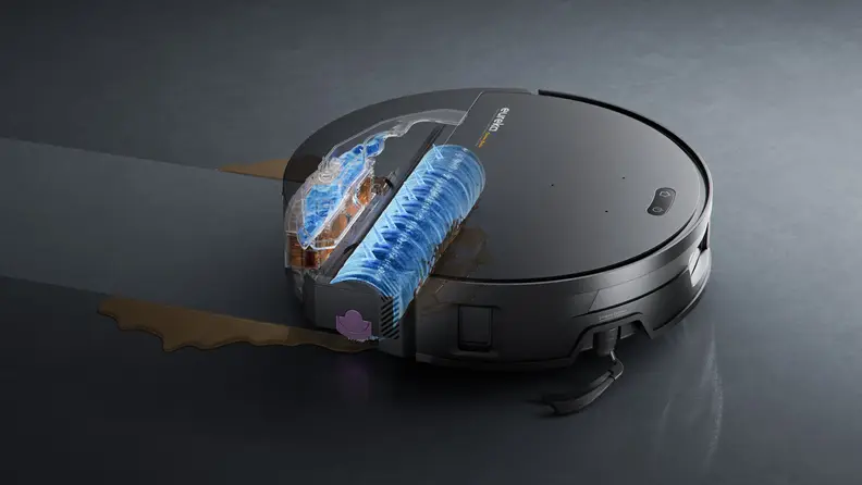 A cutaway view of a robot vacuum shows its internal roller brush actively scrubbing and collecting liquid spills on a hard floor.