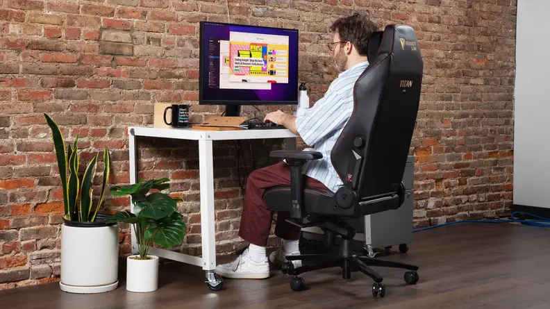 A person sitting on the chair interacting with a desktop.
